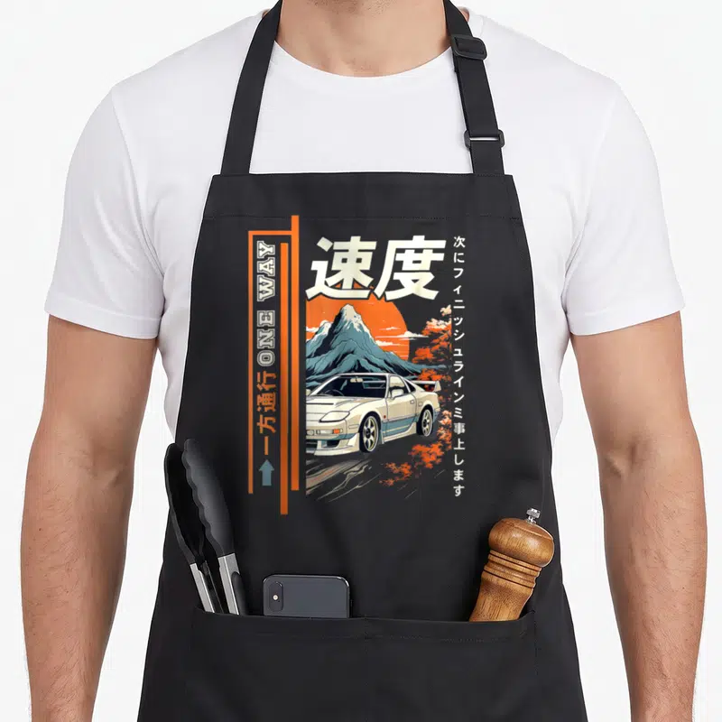 Japanese car apron - Retro white car, orange sun, blue mountain, Japanese kanji for speed, and vertical one way sign — shown on a black cotton canvas apron against a white background