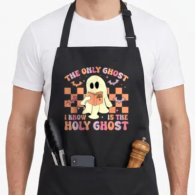 Bible halloween apron - Cream ghost holding HOLY BIBLE on orange checkerboard with pink and purple text — shown on a black cotton canvas apron against a white background