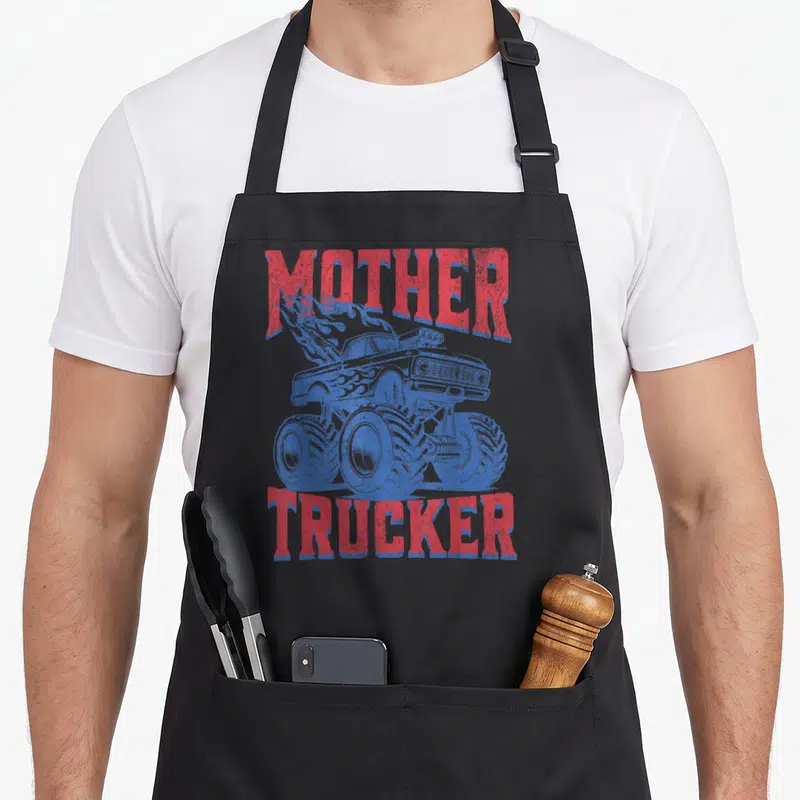 Trucker mother's day aprons - Blue monster truck with red flames and distressed MOTHER TRUCKER text — shown on a black cotton canvas apron against a white background