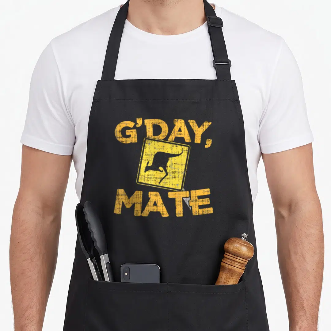 Gday kangaroo apron - Distressed yellow sign with jumping kangaroo silhouette and G'DAY, MATE text — shown on a black cotton canvas apron against a white background