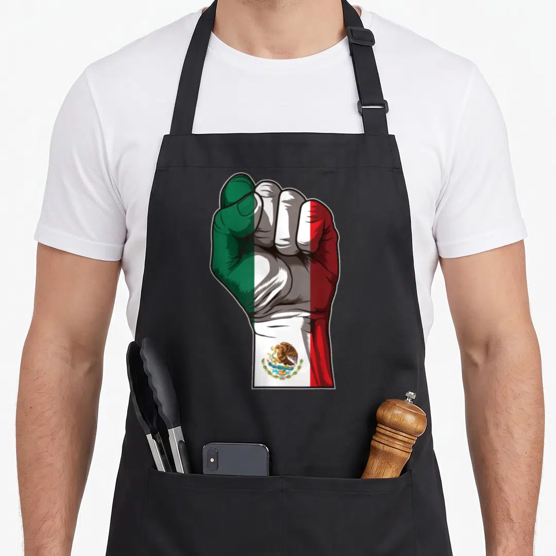 Raised mexican apron - Clenched fist painted in green, white, and red with an eagle emblem on the wrist — shown on a black cotton canvas apron against a white background