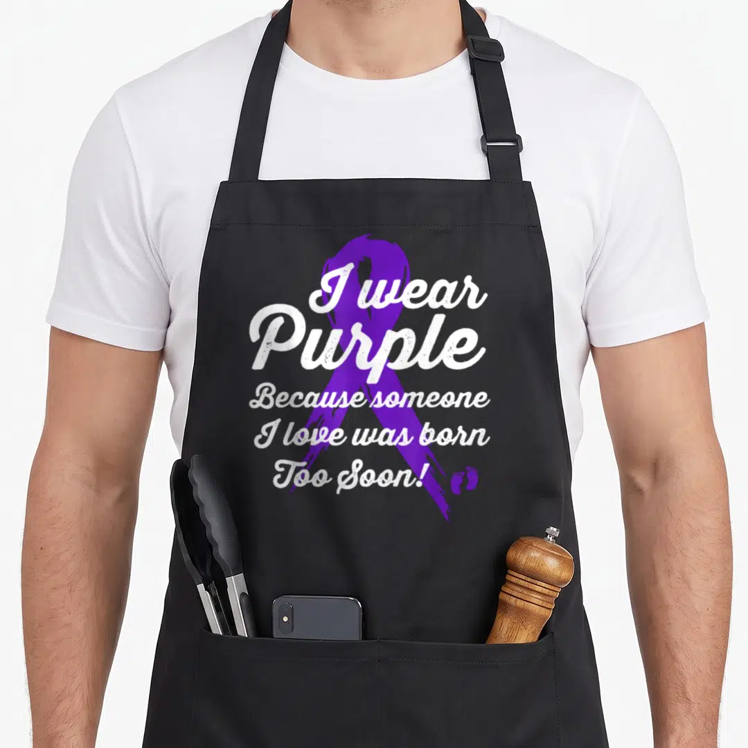Micro nicu dad apron - Distressed purple ribbon with white text I wear Purple Because someone I love was born Too Soon — shown on a black cotton canvas apron against a white background