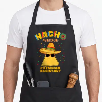 Nacho physician apron - Cartoon chip in sombrero and sunglasses with NACHO AVERAGE PHYSICIAN ASSISTANT text — shown on a black cotton canvas apron against a white background