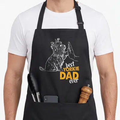 Vintage dog yorkie apron - White line-art Yorkie high-fiving hand with best YORKIE DAD ever text in orange and white — shown on a black cotton canvas apron against a white background