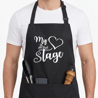 Dance ballet apron - white typography reading My Heart is On That Stage with heart shape — shown on a black cotton canvas apron against a white background