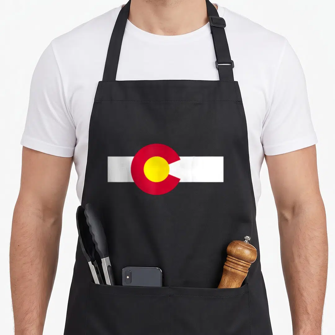 Youth colorado apron - Red circle with yellow center on white horizontal rectangle — shown on a black cotton canvas apron against a white background