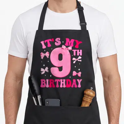 9th bow apron - Pink number 9 with IT'S MY BIRTHDAY text, bows, and stars — shown on a black cotton canvas apron against a white background
