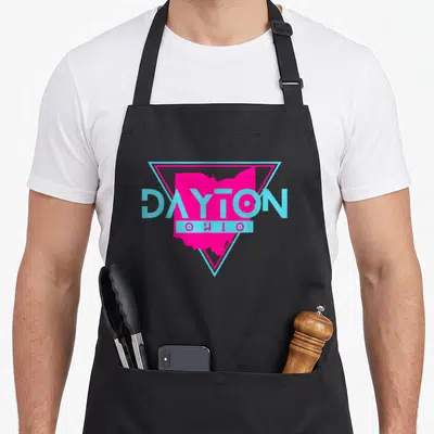 Triangle dayton apron - Retro pink Ohio map inside blue triangle with DAYTON OHIO text — shown on a black cotton canvas apron against a white background