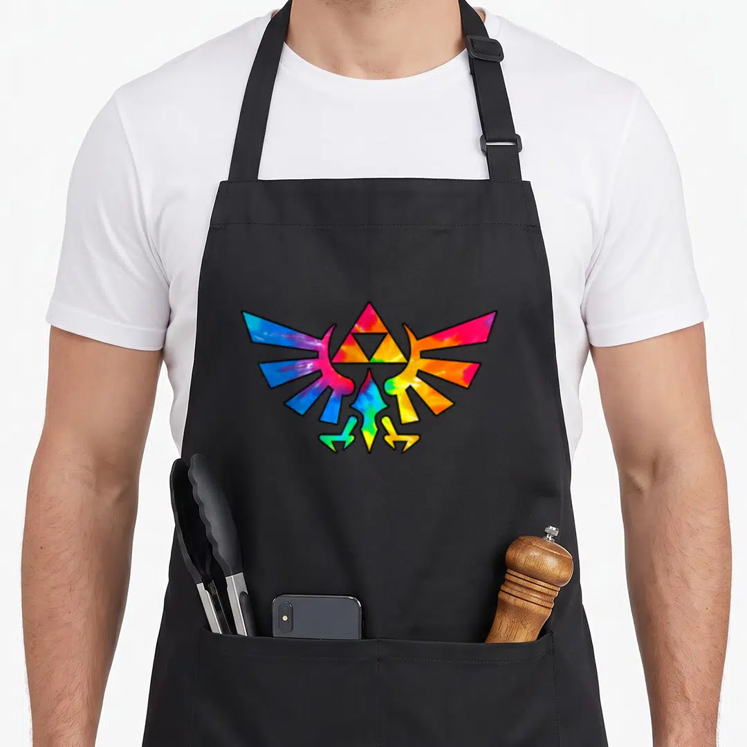 Triforce tie apron - Tie-dye Hylian Crest with Triforce center in blue red yellow green purple — shown on a black cotton canvas apron against a white background