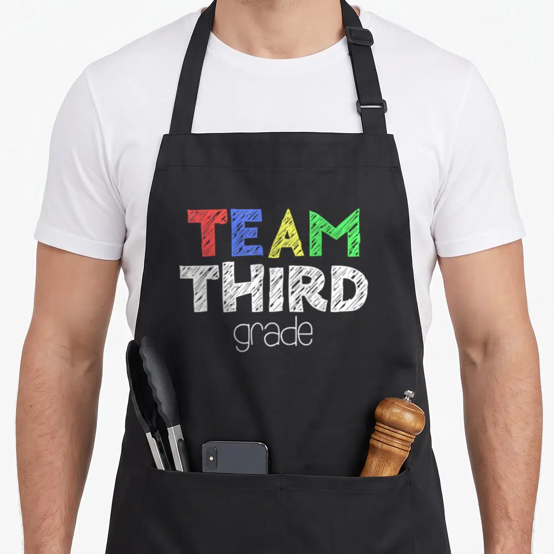 Third alumni squad apron - Stacked text reading TEAM THIRD grade in red blue yellow green and white sketch fonts — shown on a black cotton canvas apron against a white background