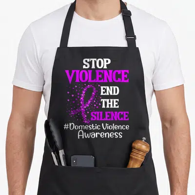 Silence domestic aprons - STOP VIOLENCE END THE SILENCE text with magenta heart ribbon and hashtag — shown on a black cotton canvas apron against a white background