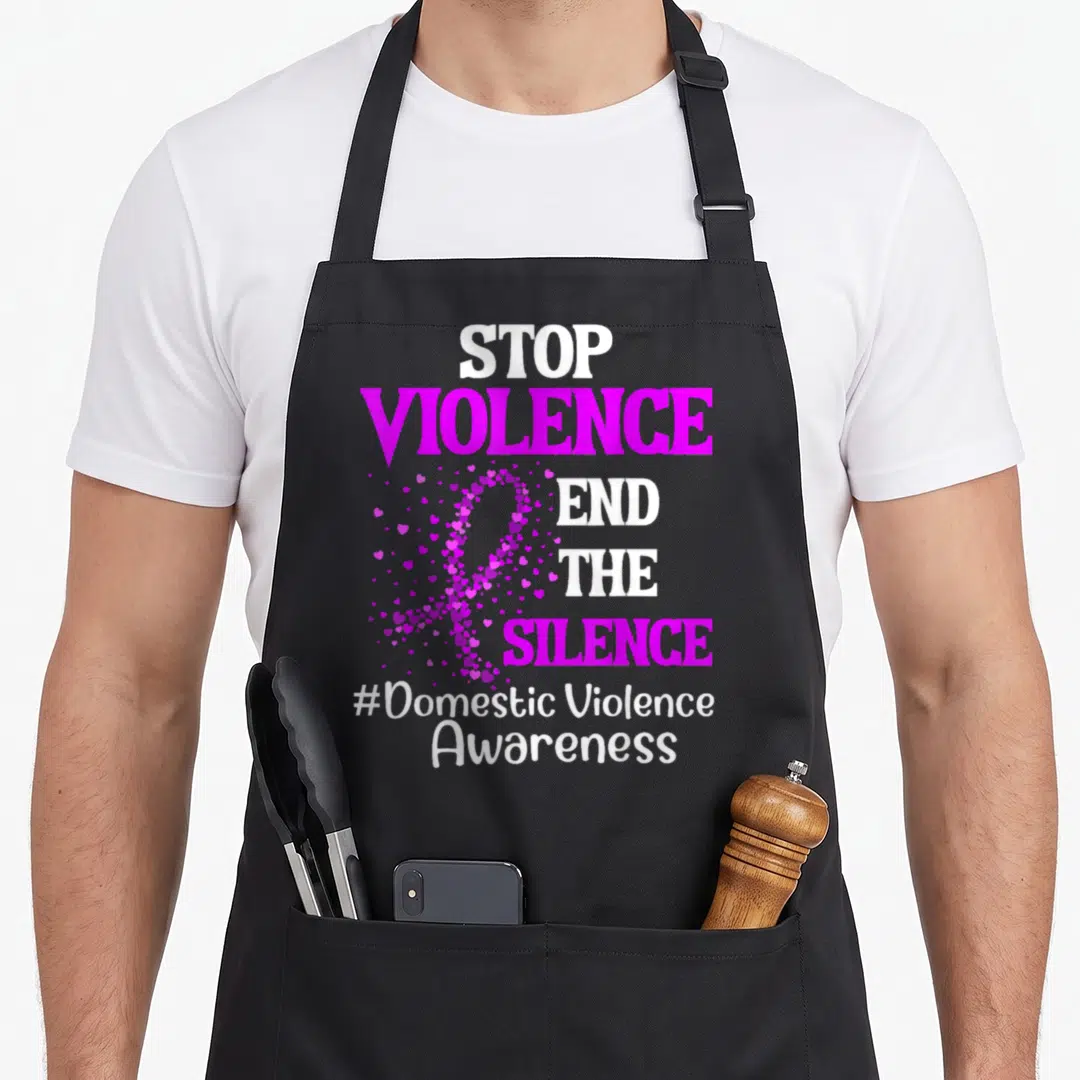 Silence domestic aprons - STOP VIOLENCE END THE SILENCE text with magenta heart ribbon and hashtag — shown on a black cotton canvas apron against a white background