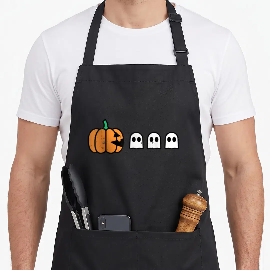 Gamer pumpkin halloween apron - Cartoon orange pumpkin with bite marks facing three white ghosts in black outline — shown on a black cotton canvas apron against a white background