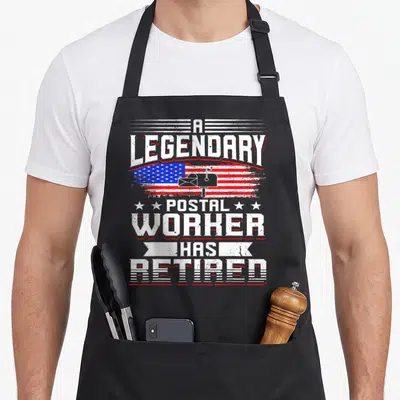 Postal mailman retirement apron - Distressed USA flag with mailbox and A LEGENDARY POSTAL WORKER HAS RETIRED text — shown on a black cotton canvas apron against a white background