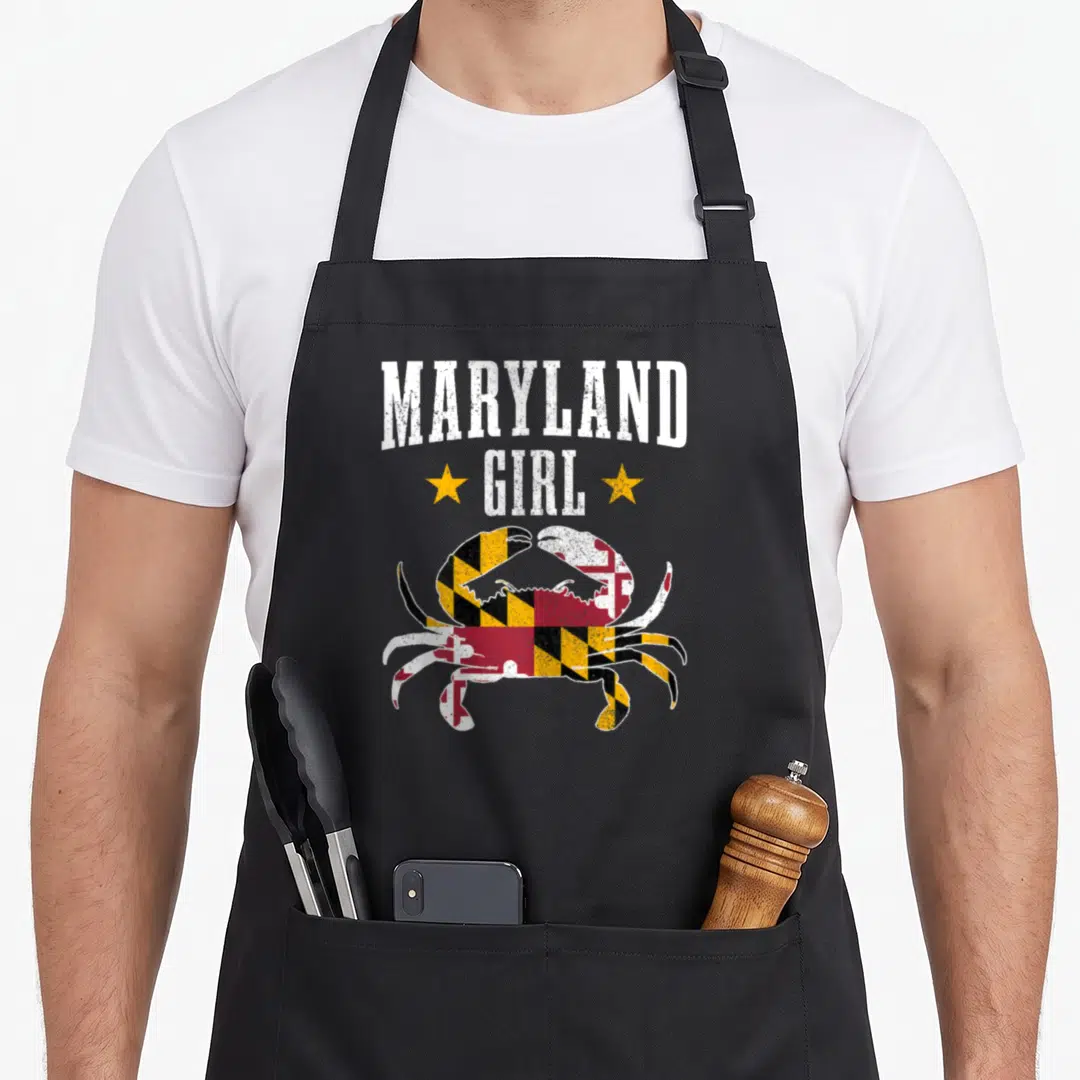 Maryland blue crab apron - Distressed crab filled with Maryland flag pattern under MARYLAND GIRL text and two stars — shown on a black cotton canvas apron against a white background
