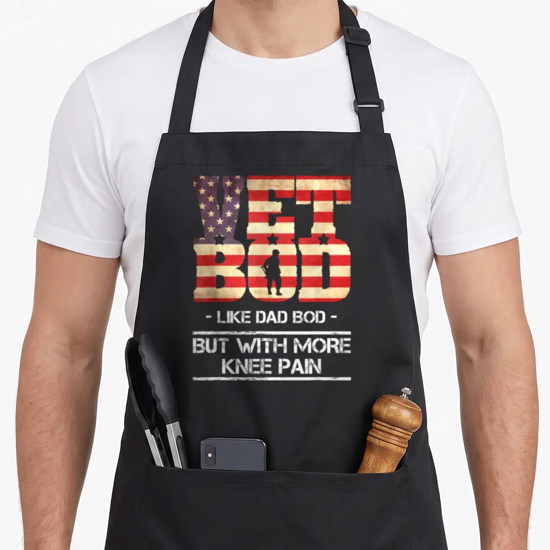 Vet dad bod apron - VET BOD flag text with soldier silhouette and knee pain quote in distressed red white blue — shown on a black cotton canvas apron against a white background