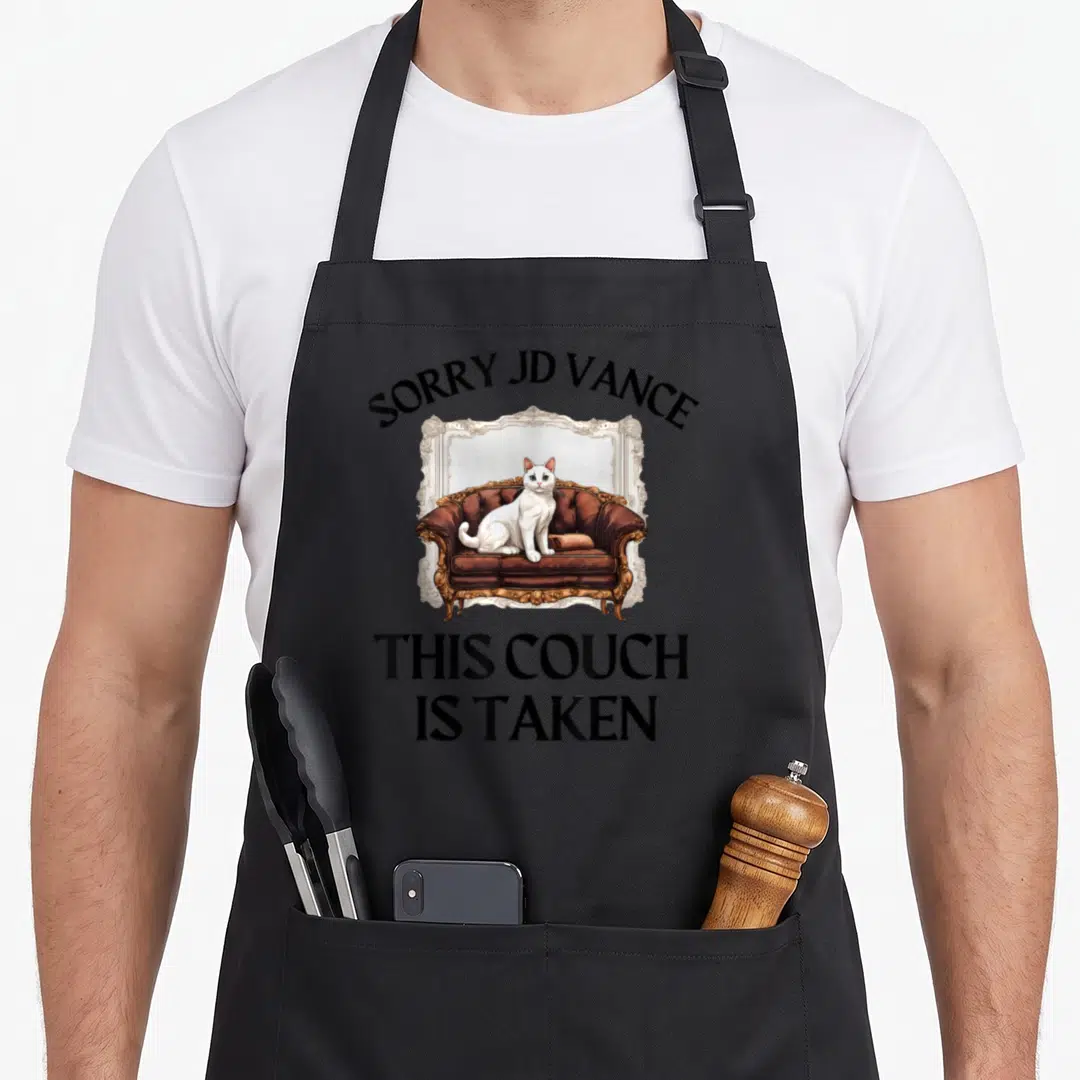 Vance cat lady apron - White cat sitting on brown ornate couch with arched text SORRY JD VANCE and stacked text THIS — shown on a black cotton canvas apron against a white background