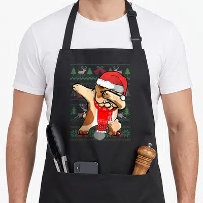 Dabbing ugly sweater apron - Cartoon bulldog dabbing in Santa hat and red scarf on knit pattern background — shown on a black cotton canvas apron against a white background