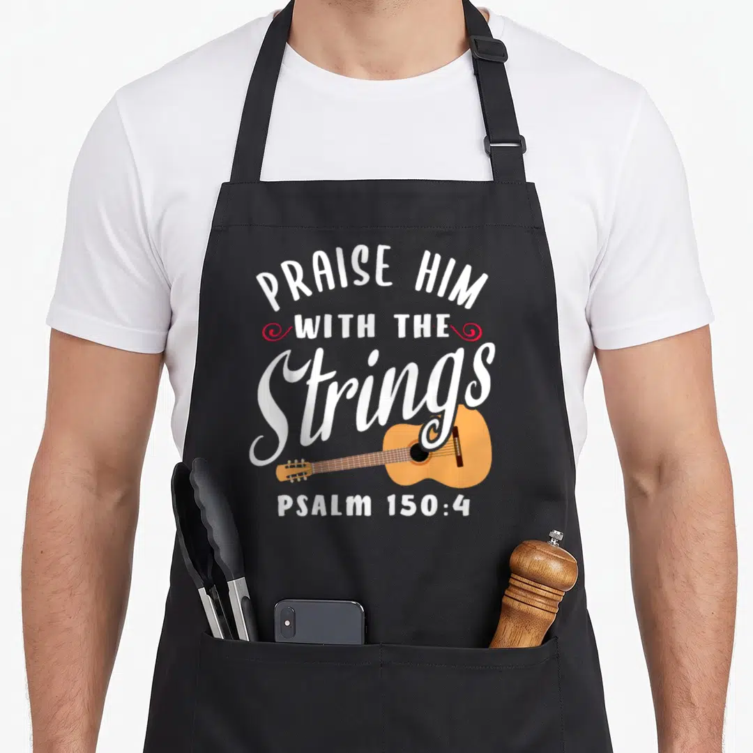 String psalm christian apron - Praise Him With The Strings PSALM 150:4 text with orange acoustic guitar and red swirls — shown on a black cotton canvas apron against a white background
