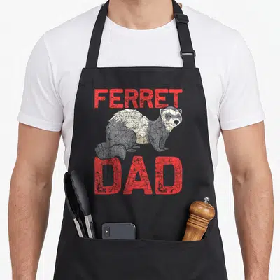 Pet ferret father day apron - Red FERRET DAD text framing a grey and white distressed cartoon ferret — shown on a black cotton canvas apron against a white background