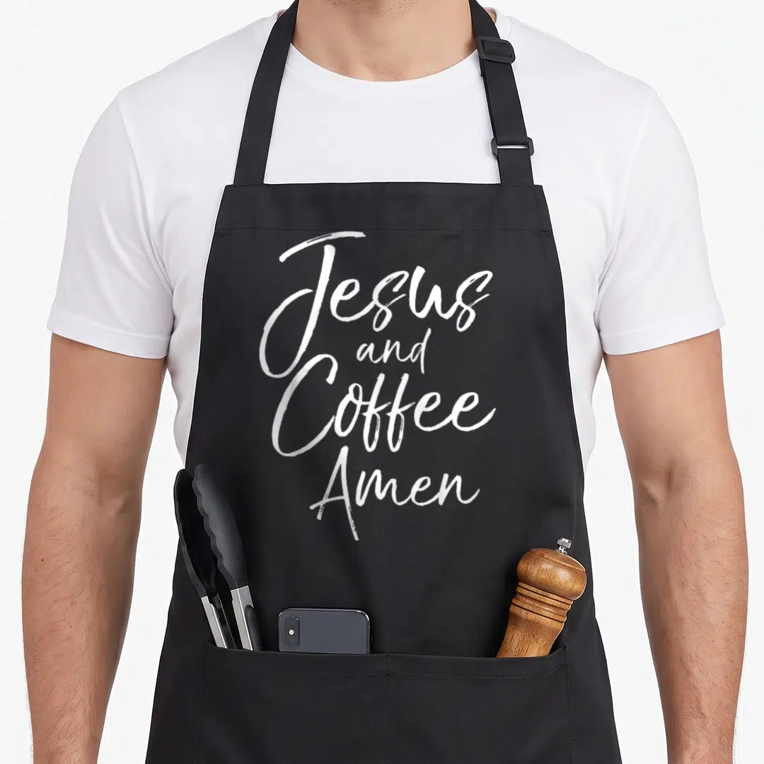 Worship coffee apron - White brush script text reading Jesus and Coffee Amen stacked vertically on dark background — shown on a black cotton canvas apron against a white background