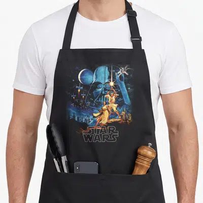 Faded new hope apron - Retro Star Wars poster art with blue Vader silhouette, Luke, Leia, ships, and logo — shown on a black cotton canvas apron against a white background