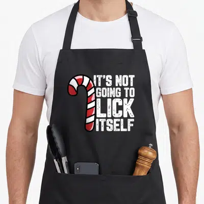 Inappropriate candy cane apron - Red and white candy cane next to stacked white text reading It's Not Going To Lick — shown on a black cotton canvas apron against a white background