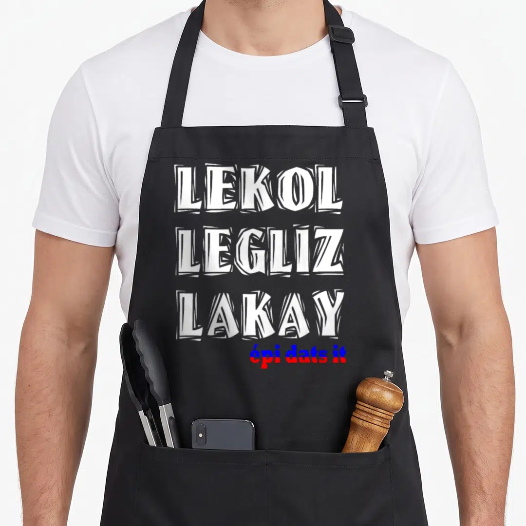 Haitian creole apron - Lekol Legliz Lakay text in white blue and red stacked vertically — shown on a black cotton canvas apron against a white background
