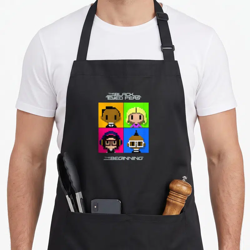 Beginning eyed apron - Four pixel art faces in colored squares with band name and album title text — shown on a black cotton canvas apron against a white background
