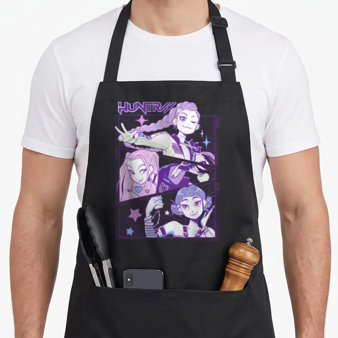 Animated hunter apron - Rumi Mira Zoey cartoon girls in diagonal panels with HUNTRX text and stars — shown on a black cotton canvas apron against a white background