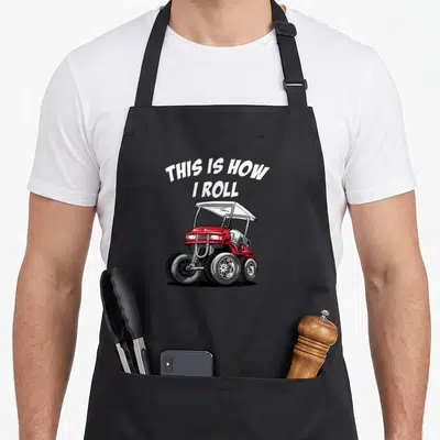 Cute roll golf apron - Red white silver cartoon golf cart with arched white text THIS IS HOW I ROLL — shown on a black cotton canvas apron against a white background