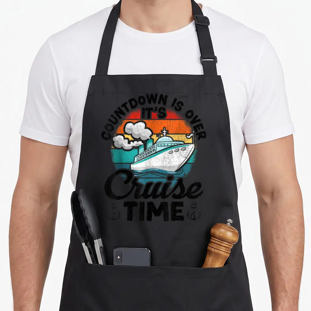 Funny cruise countdown apron - Retro ship graphic with arched text COUNTDOWN IS OVER IT'S Cruise TIME and two anchors — shown on a black cotton canvas apron against a white background