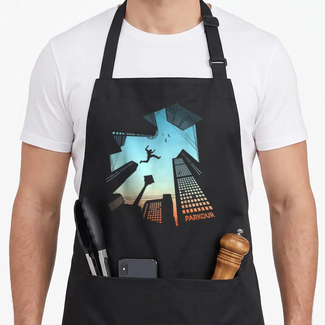 Freerunning parkour apron - Minimalist silhouette of person jumping between skyscrapers against blue orange gradient — shown on a black cotton canvas apron against a white background