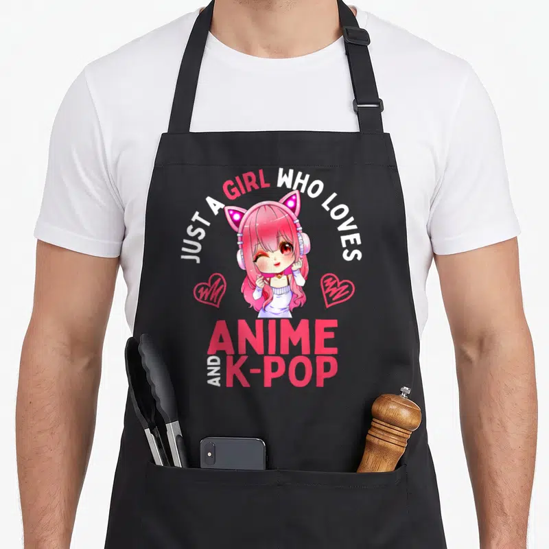 Funny pop anime apron - Pink anime girl with cat ears flanked by hearts under text about loving anime and K-pop — shown on a black cotton canvas apron against a white background