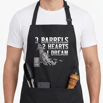 Barrel horse apron - White 3 Barrels 2 Hearts 1 Dream text next to a grey barrel racer illustration on a grey background — shown on a black cotton canvas apron against a white background