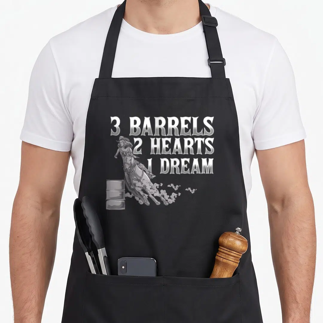 Barrel horse apron - White 3 Barrels 2 Hearts 1 Dream text next to a grey barrel racer illustration on a grey background — shown on a black cotton canvas apron against a white background