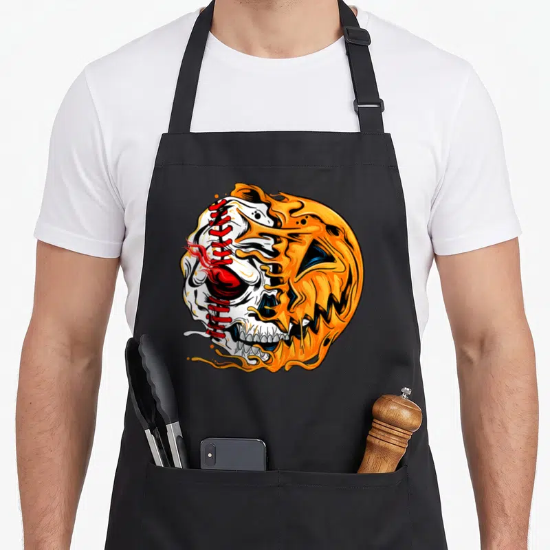 Baseball player halloween apron - Cartoon pumpkin skull with red baseball stitching and orange flame details — shown on a black cotton canvas apron against a white background