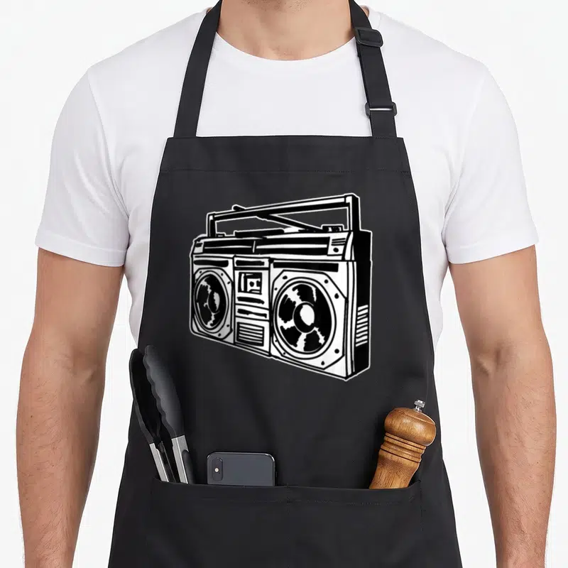 Ghetto hip apron - Black and white line art drawing of a retro boombox centered on a black apron — shown on a black cotton canvas apron against a white background