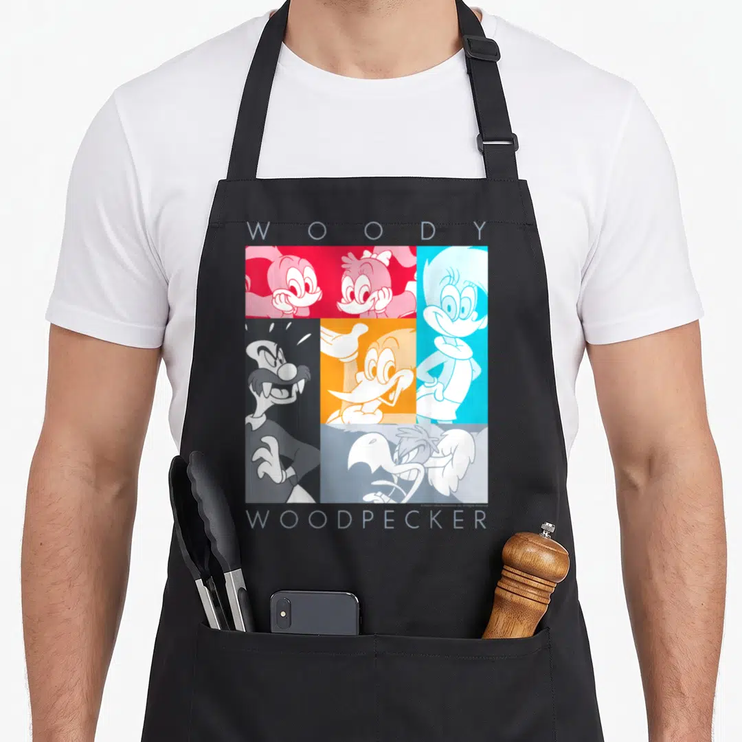Panel woodpecker apron - Cartoon grid of Woody Woodpecker characters in red blue and orange blocks with WOODY — shown on a black cotton canvas apron against a white background