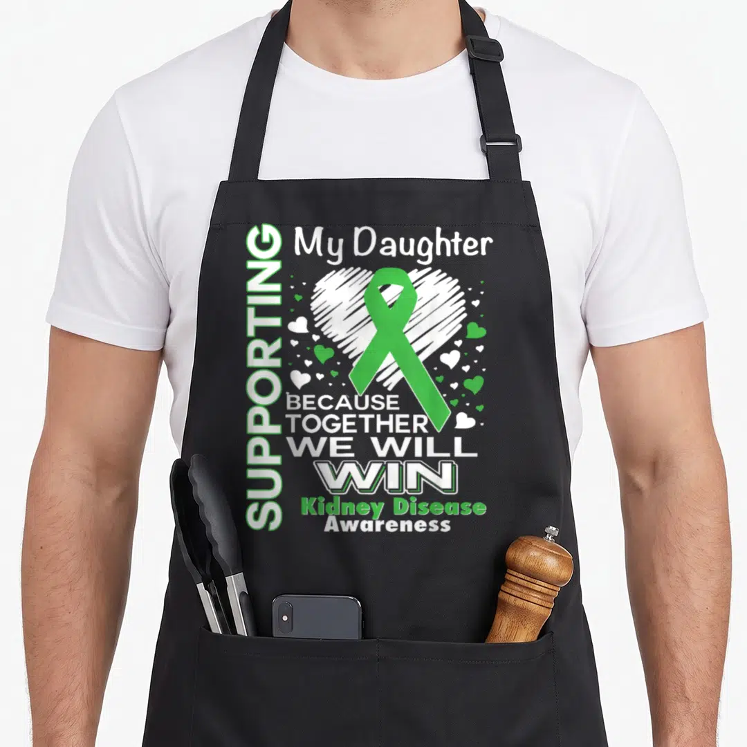 Supporting kidney disease awareness apron - Green ribbon over white heart with text supporting daughter kidney disease — shown on a black cotton canvas apron against a white background