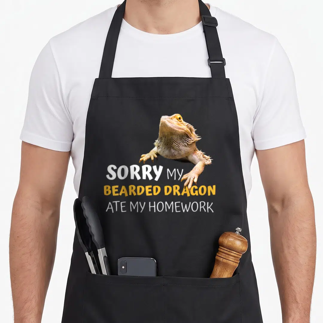 Dragon teacher apron - Bearded dragon photo above sorry my bearded dragon ate my homework text in grey, white — shown on a black cotton canvas apron against a white background