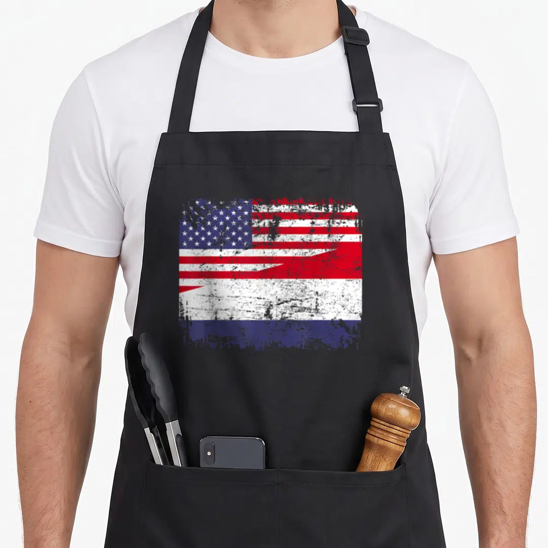Dutch american flag apron - Distressed red white and blue split flag graphic on canvas — shown on a black cotton canvas apron against a white background