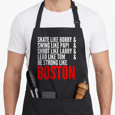 Strong boston university apron - White and red stacked text reading Skate Like Bobby Swing Like Papi Shoot Like Larry — shown on a black cotton canvas apron against a white background