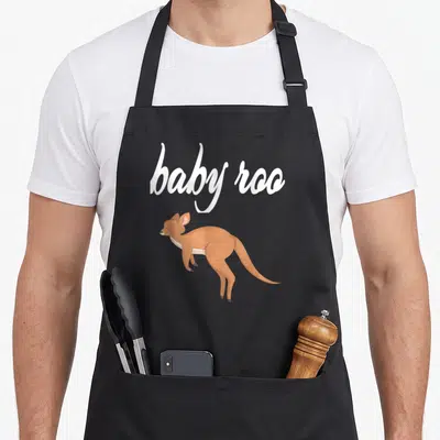 Baby kangaroo apron - White baby roo script above a brown cartoon joey kangaroo — shown on a black cotton canvas apron against a white background
