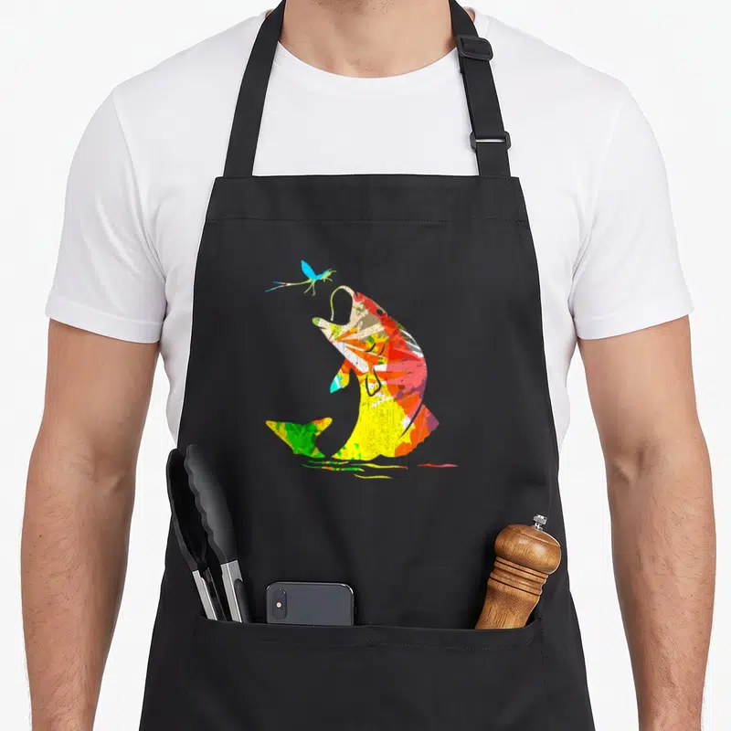 Rainbow fish apron - Watercolor multicolored fish jumping towards a blue fly — shown on a black cotton canvas apron against a white background