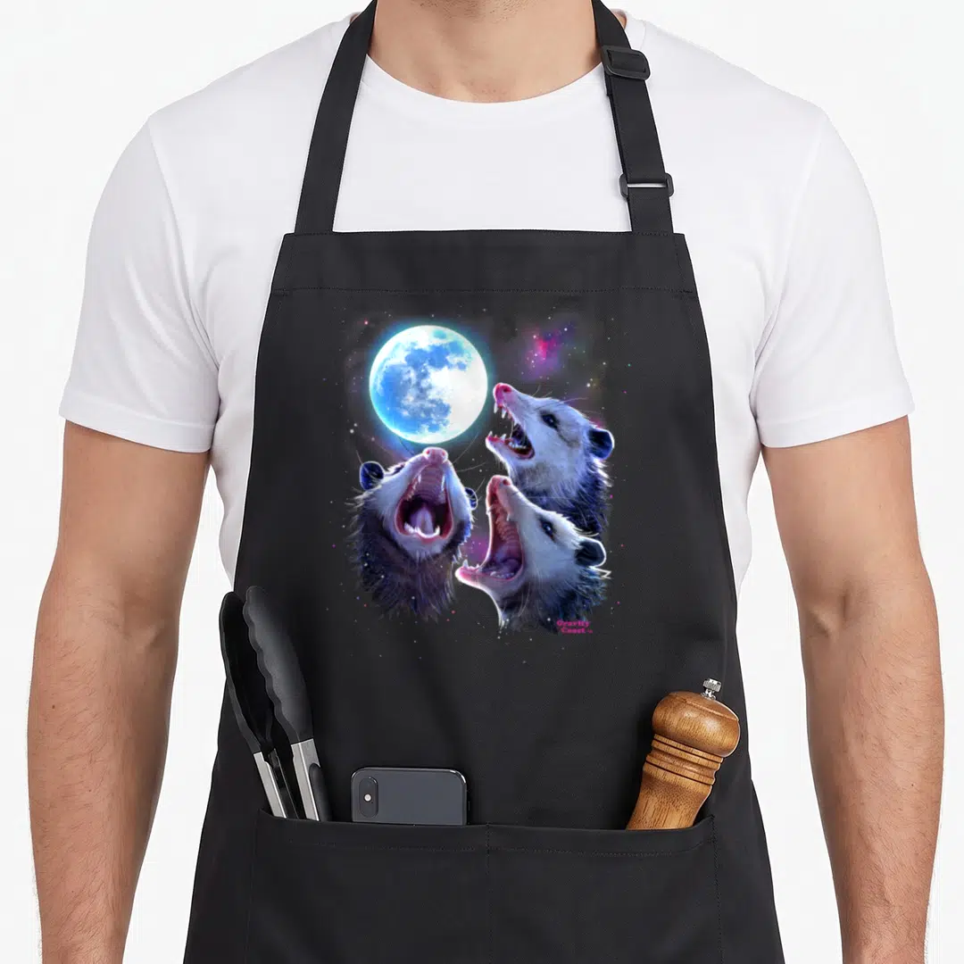 Three pet apron - Three realistic opossum heads with open mouths below a glowing blue moon and scattered stars — shown on a black cotton canvas apron against a white background
