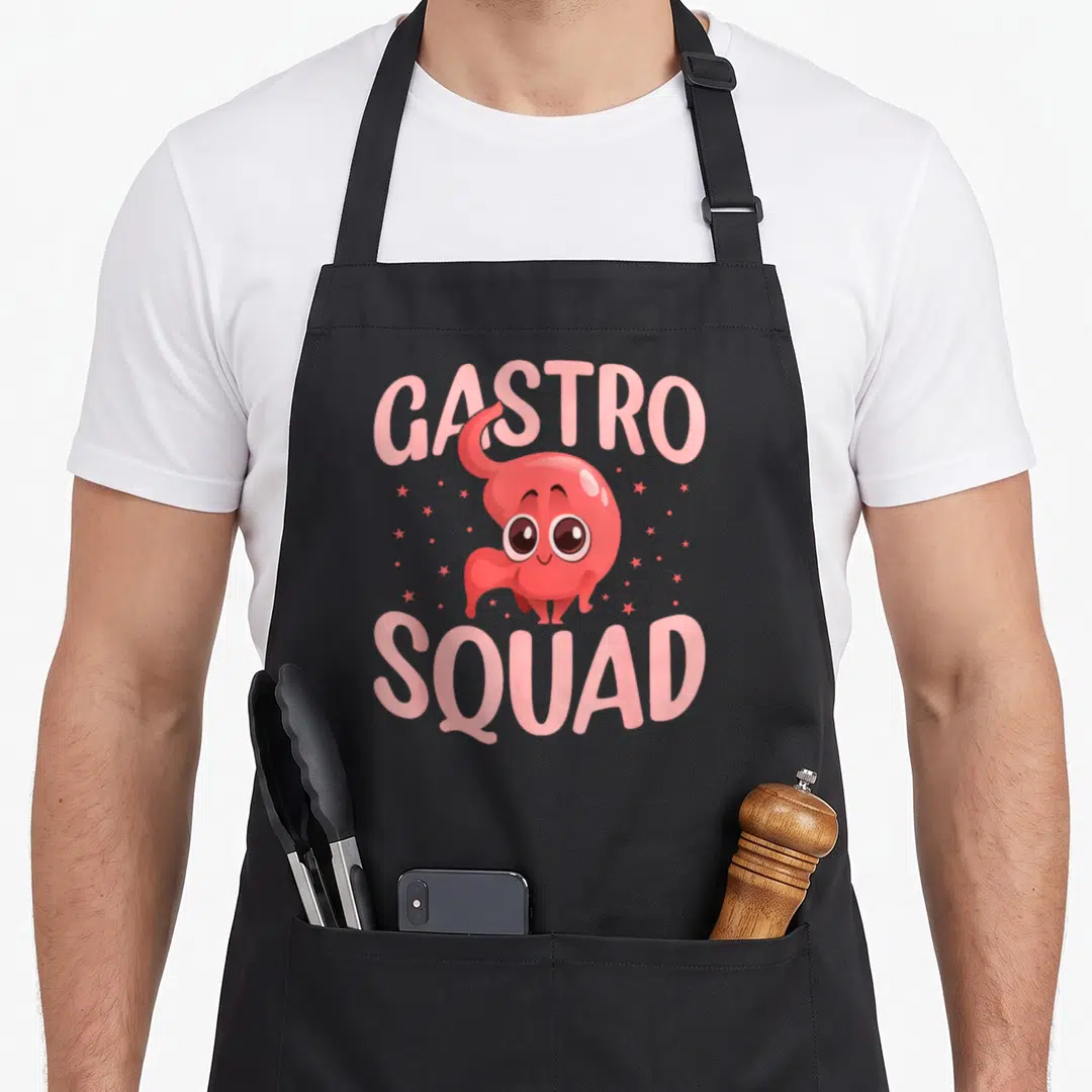 Medical assistant squad apron - Red cartoon stomach character centered between pink GASTRO SQUAD text with scattered — shown on a black cotton canvas apron against a white background