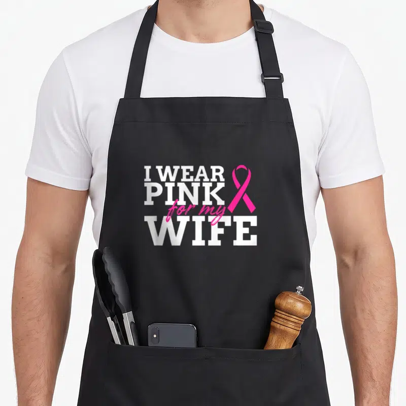 Wife breast cancer awareness aprons - I WEAR PINK for my WIFE text with pink ribbon on black background — shown on a black cotton canvas apron against a white background