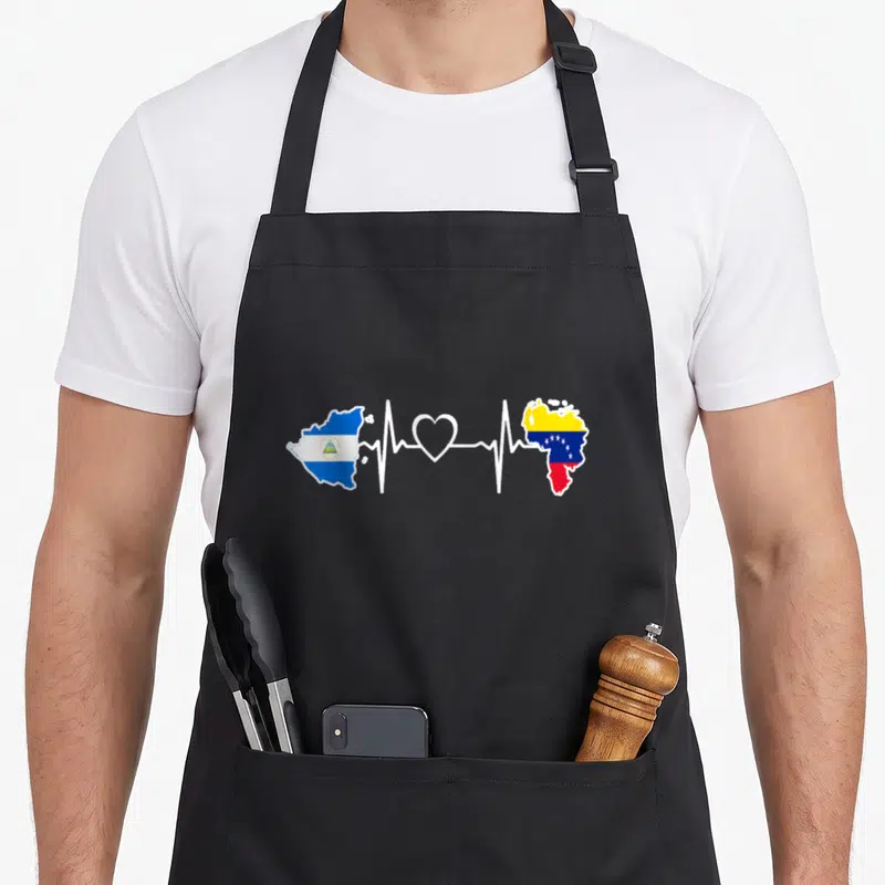 Venezuela nicaraguan girl apron - Heartbeat line connecting Nicaragua and Venezuela flag maps with a central heart shape — shown on a black cotton canvas apron against a white background