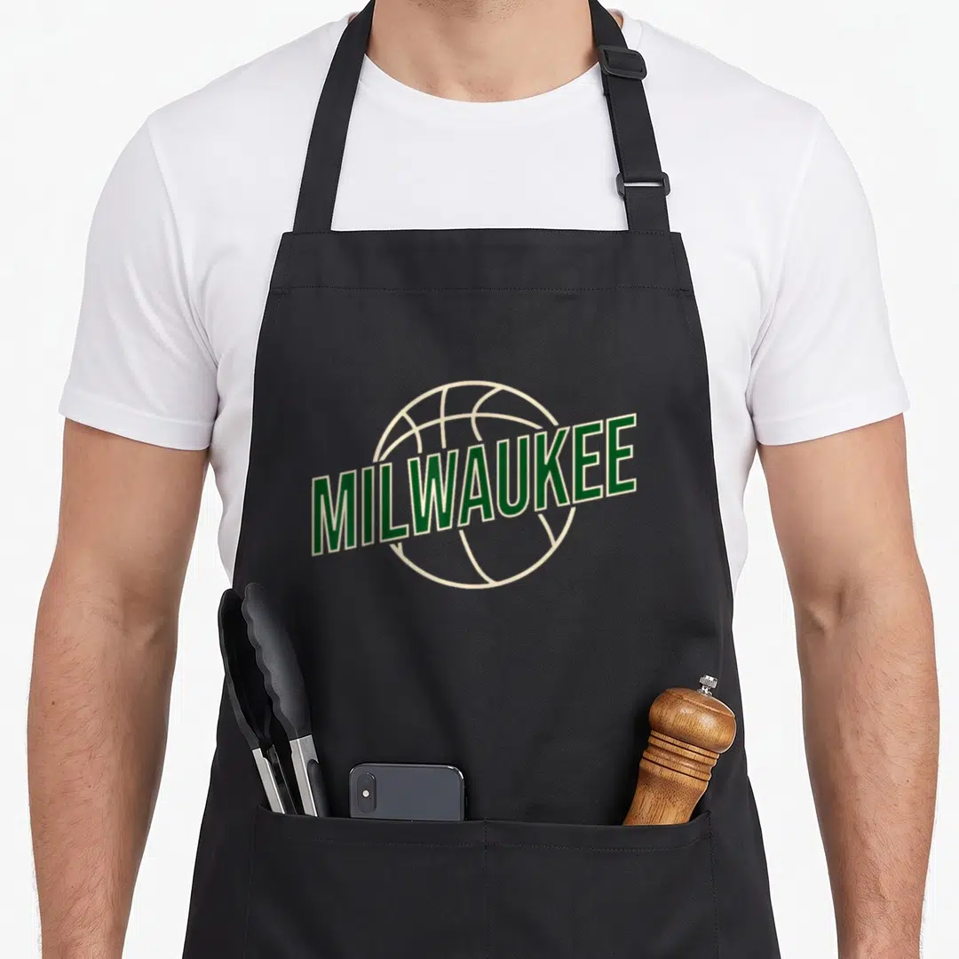 Athletic milwaukee apron - Green MILWAUKEE text overlapping an off-white basketball outline in a minimalist style — shown on a black cotton canvas apron against a white background